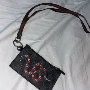 Äkta gucci kingsnake plånbok med band runt nacken - Gucci plånbok som man kan ha runt nacken med band, kommer med box ticket, dustbag men tyvärr ingen kvitto eftersom morsan slängde den   (ÄKTA)