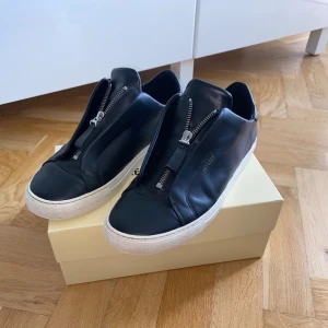 Axel arigato Clean 90 med dragkejda - Storlek 41 i svart färg. Modellen finns ej längre hos Axel arigato, men originalpriset ligger på ungefär 2400 kr. 