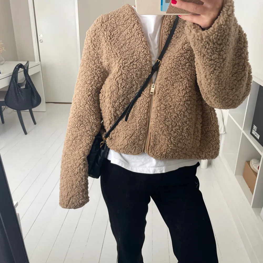 Säljer en supermysig beige teddyjacka som är perfekt för höst och vinter. Den har en dragkedja framtill och är långärmad. Jackan är croppad och ger en avslappnad look. Perfekt för att hålla sig varm och stilren samtidigt!. Jackor.