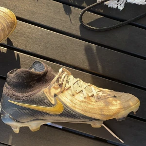 Nike Phantom Luna II Elite FG-PRO Mad Ready - Vit/Svart/Guld - Säljer mina fotbollskor pga av att de inte passa min fot. Använda några träningar 8/10  Köpta på unisport för 3149 