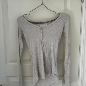Grå ribbad tröja från L.O.G.G. - Säljer en superfin grå ribbad tröja från L.O.G.G. Den har långa ärmar och en knappdetalj framtill som ger en snygg touch. Perfekt för både vardag och mysiga höstkvällar. Tröjan är i bra skick och redo för en ny ägare!