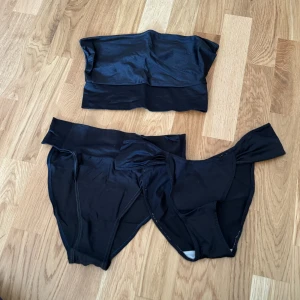 Svart bikini - Säljer en stilren svart bikini i tre delar. Överdelen är en bandeau-modell utan axelband och underdelen är en klassisk trosa. Perfekt för en dag på stranden eller vid poolen!