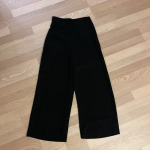 Svarta vida byxor från Zara - Snygga svarta byxor från Zara i storlek S. De är högmidjade och har en vid passform. Innerbenslängd är 63 cm.