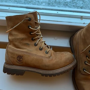 Bruna boots från Timberland - Säljer ett par klassiska bruna Timberland boots i skinn. De har en robust sula med bra grepp och snörning framtill. Perfekta för höst och vinter, både snygga och praktiska. Använda men i mycket bra skick!