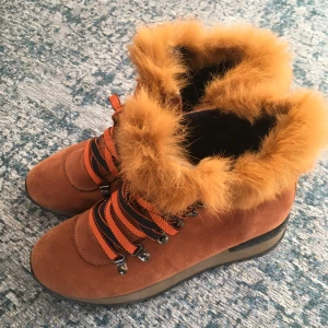 Bruna boots med pälsdetaljer - Säljer ett par snygga bruna boots i mocka med fluffig päls runt skaftet. De har svarta och orangea snören och en robust sula, perfekt för höst och vinter. Skorna är i mycket bra skick och passar både för stadspromenader och skogsturer,storlek37,5,används en gång 