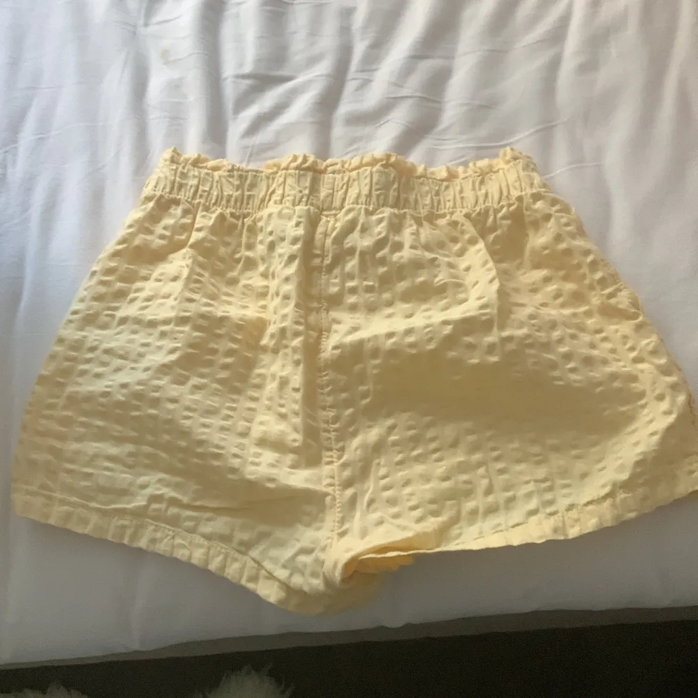 Säljer ett par supermysiga gula shorts i bomull. De har en loose passform och är perfekta för sommaren. Shortsen har elastisk midja med knytband och två praktiska fickor fram. Perfekta för en avslappnad dag på stranden eller i parken!. Shorts.