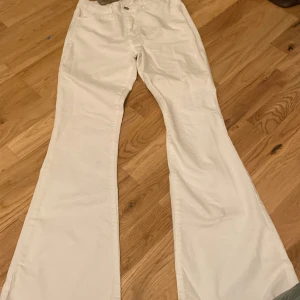 Vita bootcut jeans - Säljer ett par vita bootcut jeans i bra skick. De är högmidjade och har en klassisk femficksdesign. Perfekta för både vardag och festliga tillfällen. Passar bra till en avslappnad stil eller med en snygg topp för en mer uppklädd look.