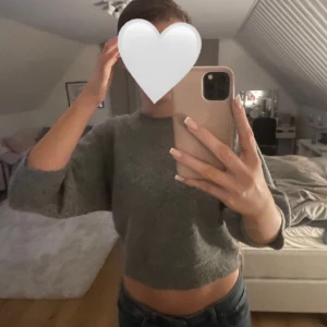 Grå stickad tröja - Säljer en supermysig grå stickad tröja med trekvartsärmar. Perfekt för kyliga dagar när du vill vara både bekväm och stilren. Tröjan är croppad och har en lös passform som ger en avslappnad look. Passar perfekt till jeans eller kjol för en casual outfit. Hör av dig vid frågor!💞💞