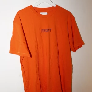 Orange t-shirt med text - Säljer en cool orange t-shirt med texten 'FRONT' på framsidan och 'BACK' på baksidan. Aldrig använd. 