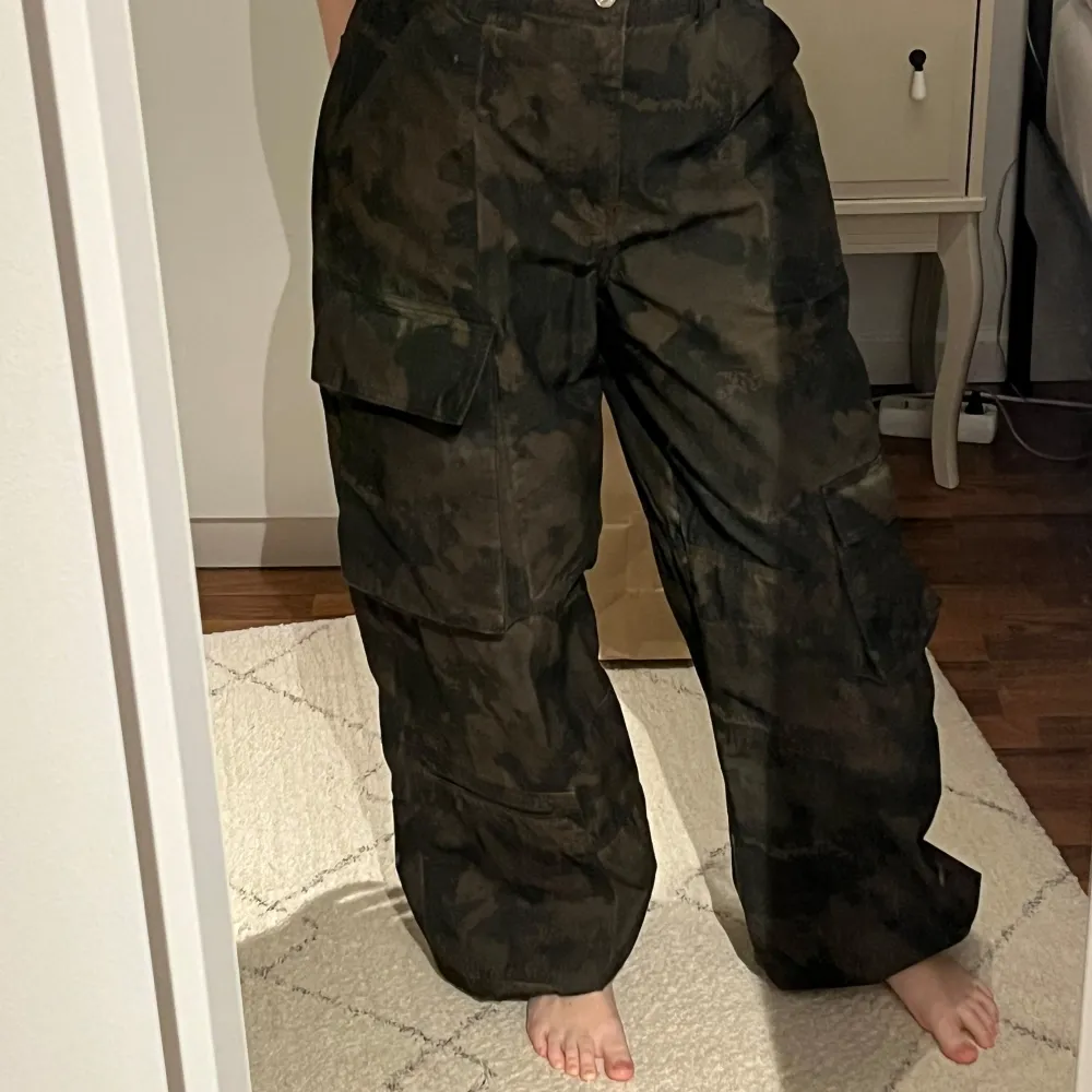 Säljer ett par grymma camouflage cargobyxor i loose fit. Perfekta för en avslappnad stil med praktiska fickor på sidorna. Byxorna är i mörkgrön färg och har även snören så man kan knyta längst ner. Mycket bra skick!😇💕. Jeans & Byxor.