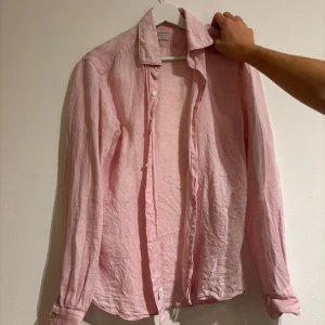 Rosa linneskjorta från Xacus - Säljer en snygg rosa skjorta från Xacus i storlek 38. Skjortan är i linne och har en skräddarsydd passform med långa ärmar och knappar framtill. Perfekt för vår och sommar! 🌸