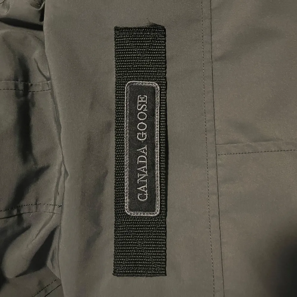 Säljer en snygg grå jacka från Canada Goose, perfekt för kyliga dagar. Jackan är i mycket bra skick och har en klassisk design med broderad logga på ärmen. Tillverkad i Kanada med högkvalitativa material. Passar perfekt för både höst och vinter.. Jackor.