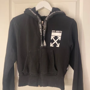 Svart hoodie från Off-White - Säljer en svart hoodie från Off-White i bra skick. Den har en dragkedja framtill och Off-White-logga på bröstet. Huvan har snören med Off-White logga. Storlek M men passa perfekt på mig som är xs-s plus passar L. Den är otroligt skön och passar olika storlekar ORDINARIE PRIS runt 1500-2000