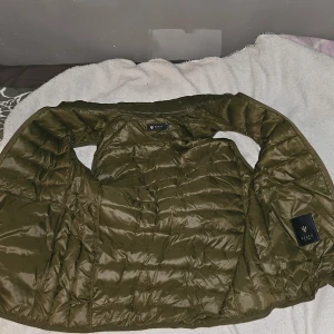 Olivgrön quiltad jacka från Riley - Säljer en olivgrön quiltad jacka från Riley. Perfekt för höst och vår med sin lätta och stilrena design. Jackan har en snygg glansig finish och är i mycket bra skick. Passar både till vardags och lite finare tillfällen. 🧥🍂