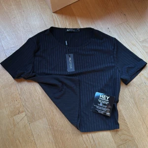 Svart ribbad topp från NLY One - Säljer en snygg svart ribbad topp från NLY One i storlek S. Toppen är kortärmad och har en stilren design som passar perfekt till både vardag och fest. Materialet är mjukt och stretchigt för en bekväm passform. Aldrig använd 🖤
