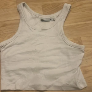 Vit ribbad linnetopp från 157 - Säljer en vit ribbad linnetopp från 157 i storlek S. Perfekt för sommardagar eller som ett basplagg i garderoben. Toppen är ärmlös och har en klassisk design som passar till det mesta. Skön och enkel att matcha med andra plagg.