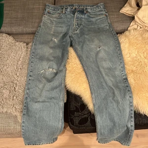 Blå jeans från Weekday - Säljer ett par blå jeans från Weekday i modellen Space Relaxed. De har en loose fit och är i bra skick med några snygga slitningar för en cool look. Perfekta för en avslappnad stil och passar till vardag. Knappgylf och klassisk femficksdesign.