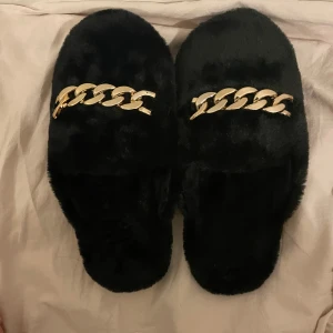 Svarta mjuka tofflor med detalj - Säljer ett par svarta jättemjuka innetofflor med gulddetalj i storlek 37/38. Oanvända. Köparen betalar frakten!