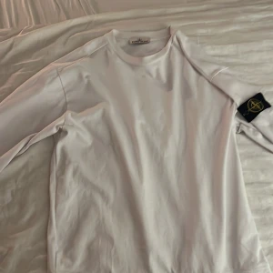 Stone Island crewneck - Säljer en stilren vit tröja från Stone Island. Den har en klassisk design med långärmade ärmar och en snygg logga på ärmen. Perfekt för både vardag och fest. Tröjan är i mycket bra skick och redo för en ny ägare! Priset är ej hugget i sten.