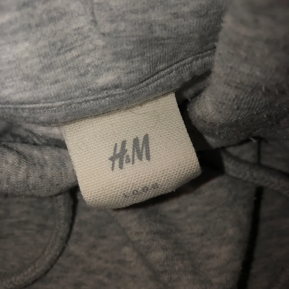 Säljer en supermysig grå hoodie från H&M i storlek XS. Den har en stor rosa text 'AMOUR' på framsidan och en klassisk känguruficka. Perfekt för chilliga dagar eller som en extra lager under jackan. Huvan har dragsko för justering. 🩶. Tröjor & Koftor.