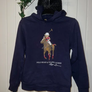 Mörkblå hoodie från Ralph Lauren - Säljer en snygg mörkblå hoodie från Ralph Lauren med en cool Polo Bear-design på framsidan.  Den är i mycket bra skick. L/G 14-16
