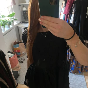 Svart spetsblus - Säljer en elegant svart blus med spets och korta ärmar. Perfekt för festliga tillfällen. Blusen har en fin struktur och en klassisk look. Passar bra till både sommar och höst.