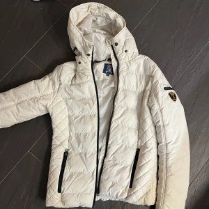 Vit quiltad jacka från Vinson Polo Club - Säljer en snygg vit quiltad jacka från Vinson Polo Club i storlek S. Jackan har en dragkedja framtill och praktiska fickor med dragkedjor. Den har en huva och märke på armen jätte fin nu till vintern pris kan diskuteras 
