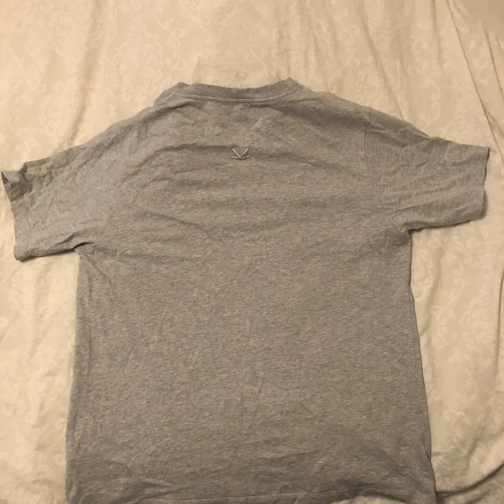 Säljer en snygg grå t-shirt från Kenzo i storlek L. Den har en klassisk passform med korta ärmar och ett stilrent tryck i blått på framsidan. Perfekt för en avslappnad look eller att matcha med jeans. T-shirten är i bra skick och den sitter som S. T-shirts.