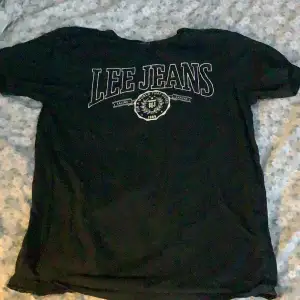 Säljer en svart t-shirt från Lee Jeans i storlek S. Den har ett stort tryck med 'Lee Jeans' på framsidan. Perfekt för en avslappnad stil och passar till vardags. T-shirten är i bomull och har en normal passform.