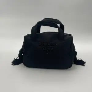 Prada Nylon Hand Bag  Skick: B/C, väldigt fint vintage skick. Se alltid bilder för egen uppfattning.  Serienummer: 45  Sku: V008  Mått: B22cm x H14cm x D11.5cm x Handle Drop 7cm