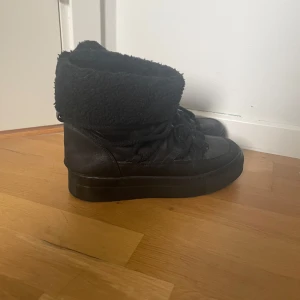 Svarta boots med pälsdetalj - Säljer ett par svarta boots i skinn med mysig pälsdejtalj runt skaftet. Det har snörningar framtill och är varma och sköna ut för vintern. 