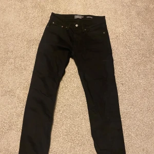 Svarta jeans från Dressmann - Säljer ett par svarta jeans från Dressmann i storlek 31/30. De har en regular fit och är perfekta för både vardag och fest. Nypriset är 599 och säljer de för använder inte de. Skicket är 10/10