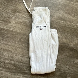 Vita mjukisbyxor från Lexington - Superbekväma vita mjukisbyxor från Lexington i storlek XS. Perfekta för en chill dag hemma eller en avslappnad promenad. Byxorna har en elastisk midja med snörning och en diskret Lexington-logga på sidan. Materialet är mjukt och skönt, vilket gör dem till ett måste i garderoben!