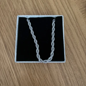 Silverfärgad halskedja i stål - Snygg och stilren halskedja i silverfärgat stål med en tvinnad design. Perfekt för både vardag och festliga tillfällen. Kedjan har en robust känsla och kommer i en elegant presentask. Ett måste för den som vill ha en tidlös accessoar!