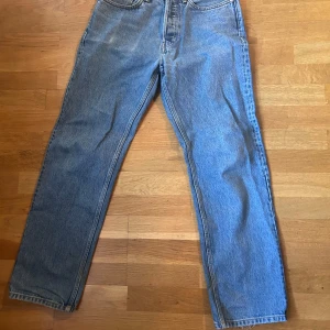 Blå jeans i bra skick - Säljer ett par klassiska blå jeans i bra skick. De har en straight/baggy passform och är tillverkade i slitstarkt denim. Perfekta för vardagsbruk och kan matchas med det mesta. Något slitna längst ned för en avslappnad look.