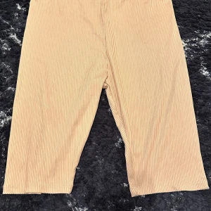 Beige ribbade shorts - Säljer ett par beige ribbade shorts i nyskick. De är perfekta för sommaren med sin bekväma passform och stilrena design. Passar både till vardags och festliga tillfällen. Perfekt för dig som vill ha något enkelt men ändå snyggt! 🌟