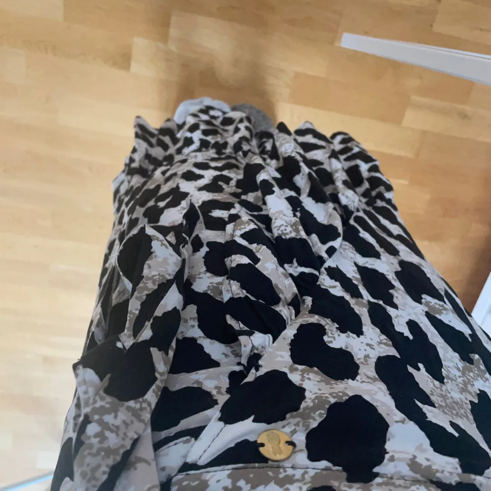 Säljer en superfin leopardmönstrad omlottkjol i svart och beige. Kjolen har en knytning i midjan och en volangdetalj längst ner. Aldrig använd, storlek 38. Från Pernilla Wahlgren collection. . Kjolar.