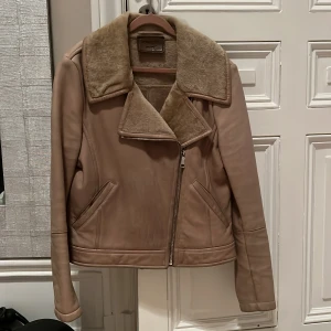 Beige skinnjacka från Prada - Säljer en snygg beige skinnjacka i bikermodell från Prada med lamullsfoder och en klassisk stilren design. Nypris 60.000. 