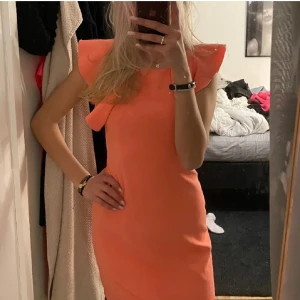 Klänning med volang - Säljer denna söta korallfärgade klänning med volanger vid axlarna. Kan vara Vero Mods är osäker, har klippt bort lappen. V ringad i ryggen, stretchigt material.🌸