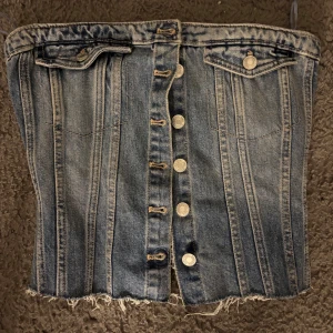 Jeans korsett från Zara - Snygg jeans korsett från Zara med knappar framtill och dekorativa fickor.