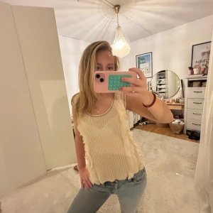 Topp - Säljer en snygg beige ribbad linnetopp med volangdetaljer. Perfekt för en avslappnad stil. Toppen är ärmlös och har en bekväm passform.