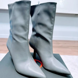 Grå stövletter med spetsig tå - Snygga grå stövletter med spetsig tå och hög klack. Perfekta för att ge en elegant touch till din outfit. Tillverkade i ett stilrent material som passar till många olika tillfällen.