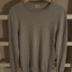 Grå tröja från John Henric - Säljer en stilren grå tröja från John Henric. Tröjan är långärmad och har en klassisk rund halsringning. Perfekt för en minimalistisk look.