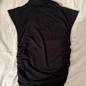 Svart ärmlös topp - Snygg svart ärmlös topp med hög krage. Den kommer från gina tricot och har en tight passform, perfekt för finare tillfällen men också till vardags 