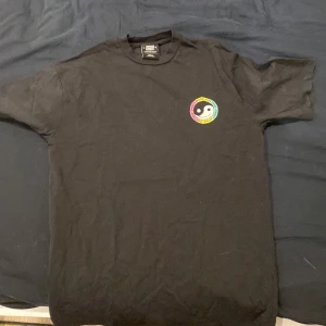 Sweet skbts tröja  - Cool svart t-shirt från Sweet SKTBS med ett färgglatt yin-yang-tryck på bröstet och ryggen. Näst intill oanvänd 