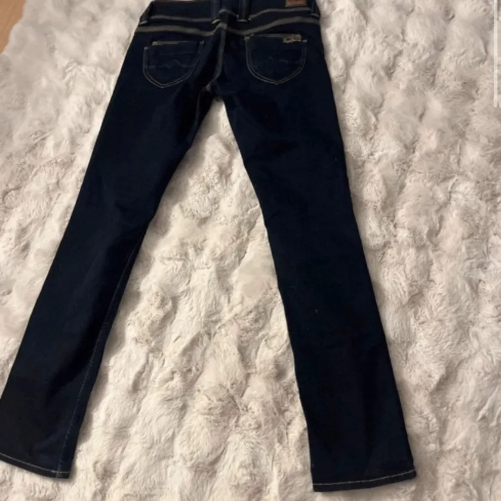 Snygga mörkblå bootcut jeans med låg midja och klassisk femficksdesign. Perfekta för en avslappnad stil med en touch av retro. Passar bra med sneakers eller klackar för en mer dressad look. W31 L34. Dom är små i storleken och passar mig som är en 27-28 . Farkut & Housut.