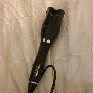 Fashion Curler - Snygg och modern Fashion Curler i svart med sladd. Perfekt för att skapa lockar med enkelhet. Den har en ergonomisk design och två knappar för enkel användning.