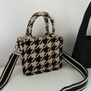 Rutig handväska med axelrem - Snygg handväska med klassiskt svart och beige hundtandsmönster. Väskan har både handtag och en justerbar axelrem för extra bekvämlighet. Perfekt för att ge din outfit en stilfull touch.