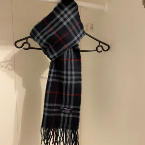 Burberry - Säljer nu denna Snygga halsduk från Burberry i blått. Tillverkad i 100% mjuk kashmir med klassiskt fransad kant. Perfekt för att hålla dig varm och stilren under kyliga dagar. Hör av er vid funderingar☺️