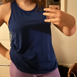 Mörkblå ärmlös linnetopp - Säljer en snygg mörkblå ärmlös linnetopp perfekt för träning. Toppen har en enkel och stilren design med rund halsringning. Passar utmärkt för aktiva dagar.